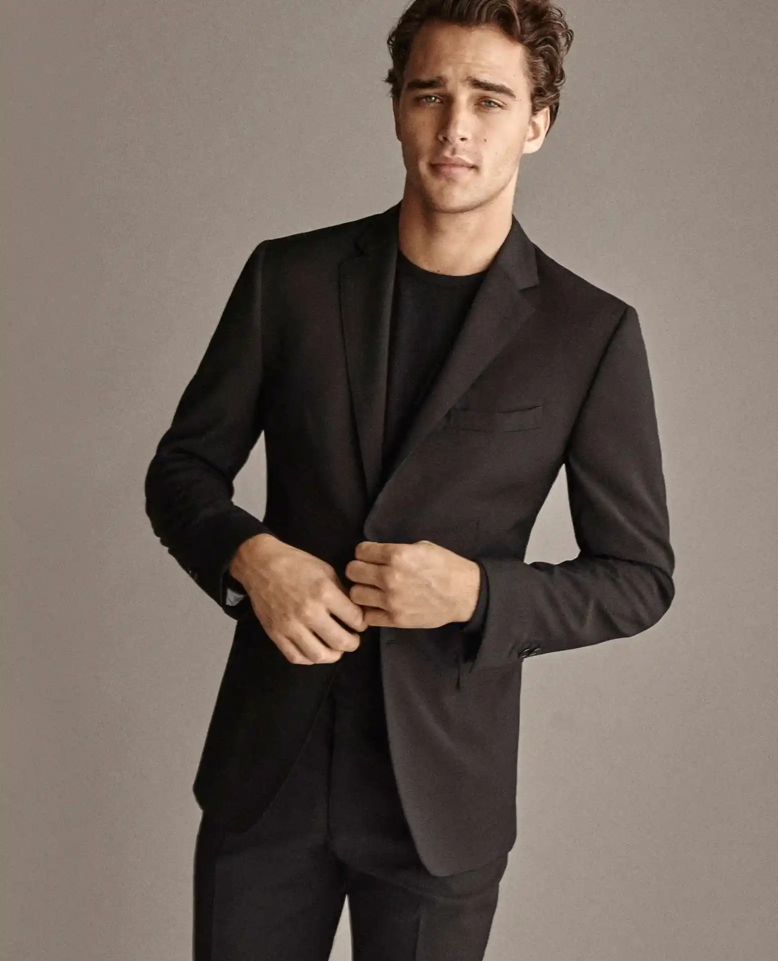 Traje negro slim fit con solapa notch y camiseta negra, look smart casual moderno, medio cuerpo fondo neutro — renta en Masculino.do