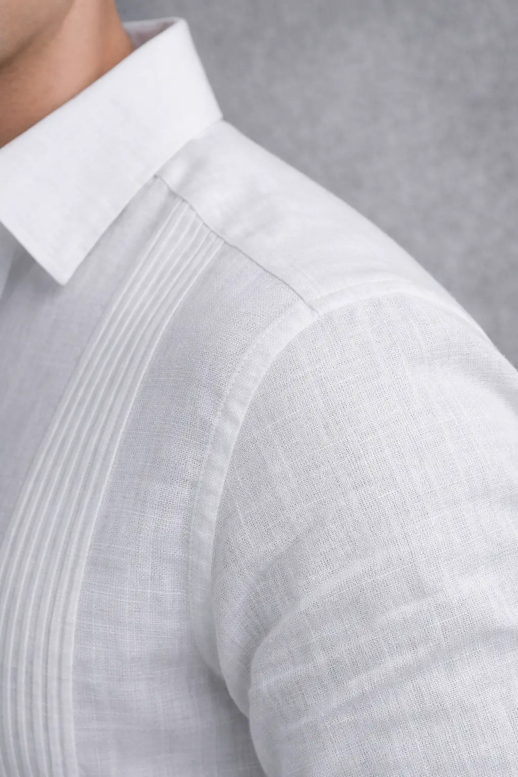 Detalle de alforzas y textura de lino en chacabana blanca sin bolsillo, vista de cuello camisero y hombro