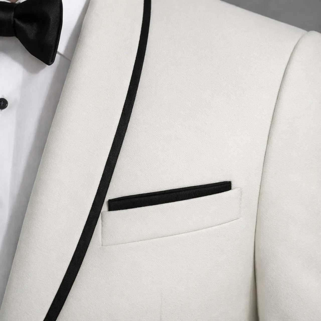 Detalle de tuxedo marfil con solapa chal ribeteada en negro y pañuelo negro, primer plano — Masculino.do