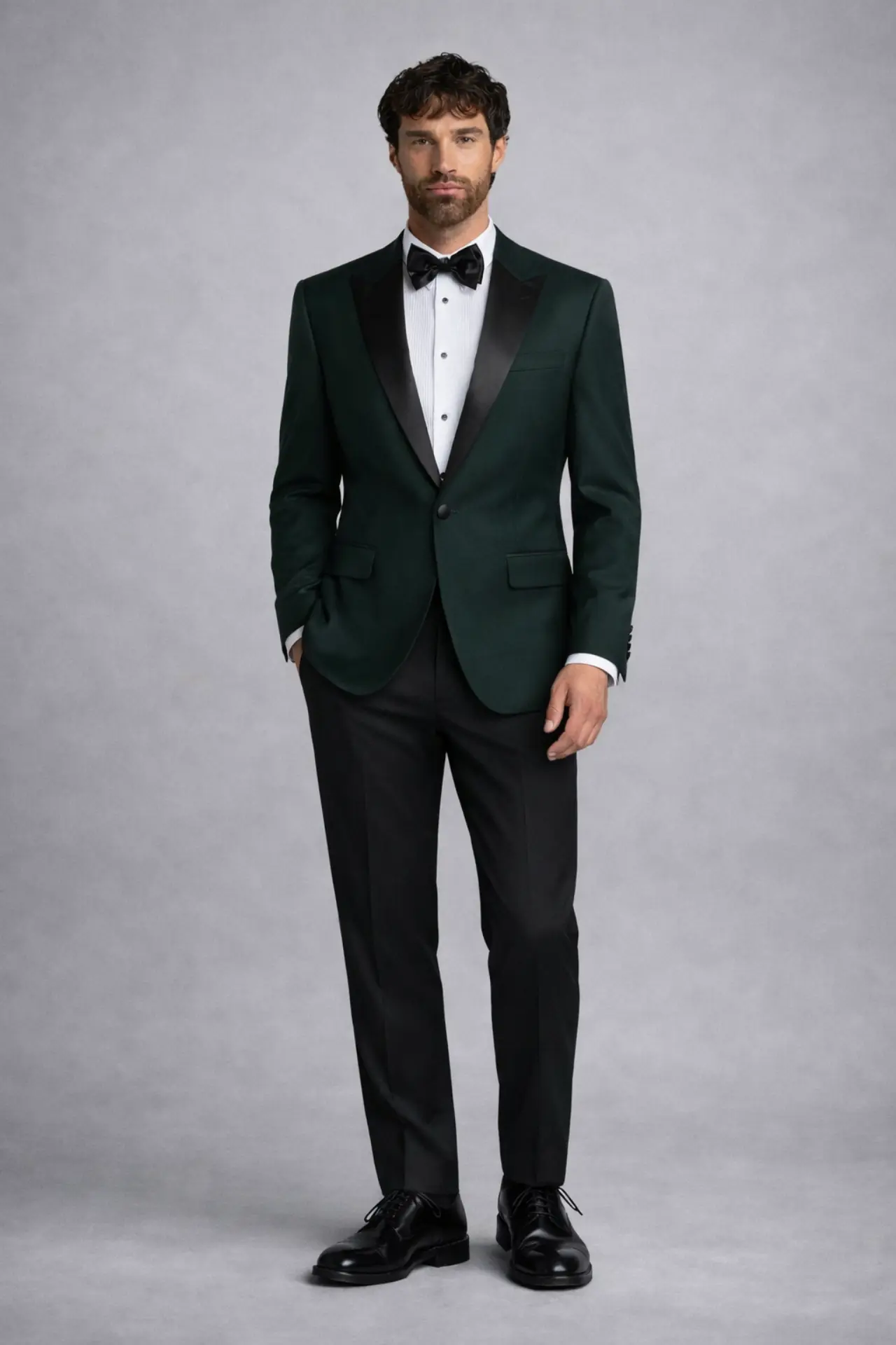 Tuxedo verde esmeralda slim fit con solapa peak en satín negro, camisa blanca y corbatín negro, fondo oscuro — venta y renta en Masculino.do