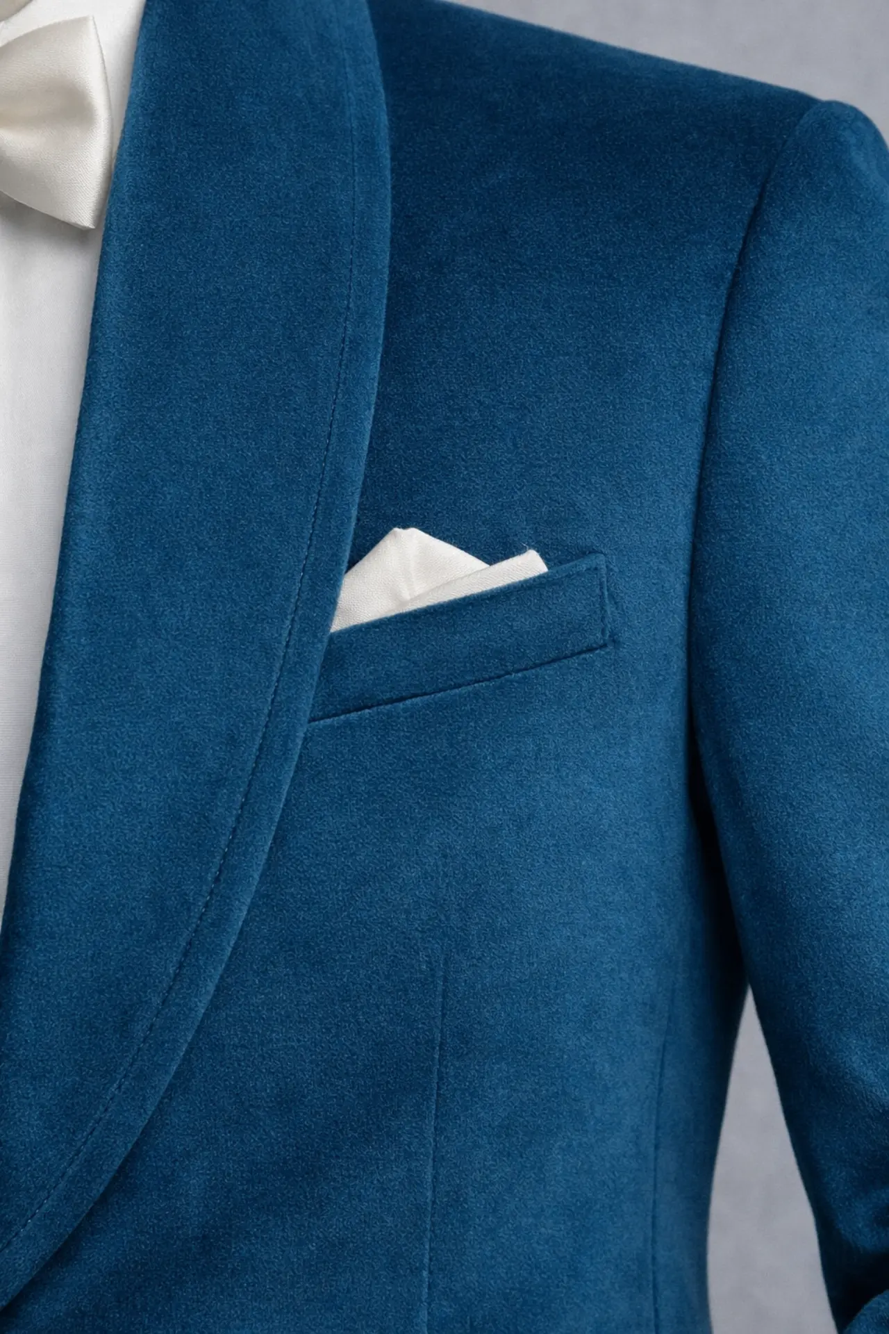 Detalle de textura velvet azul petróleo con solapa shawl y pañuelo blanco de bolsillo, primer plano — Masculino.do