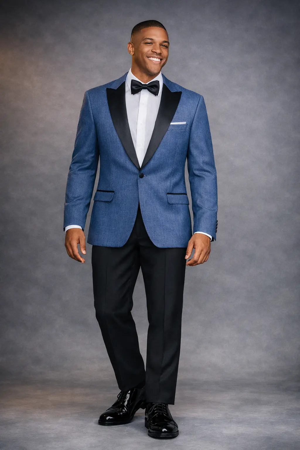 Tuxedo navy en tejido denim con solapa peak en satín negro italiano, corbatín negro, pañuelo blanco y pantalón negro, cuerpo completo fondo gris — renta y venta en Masculino.do