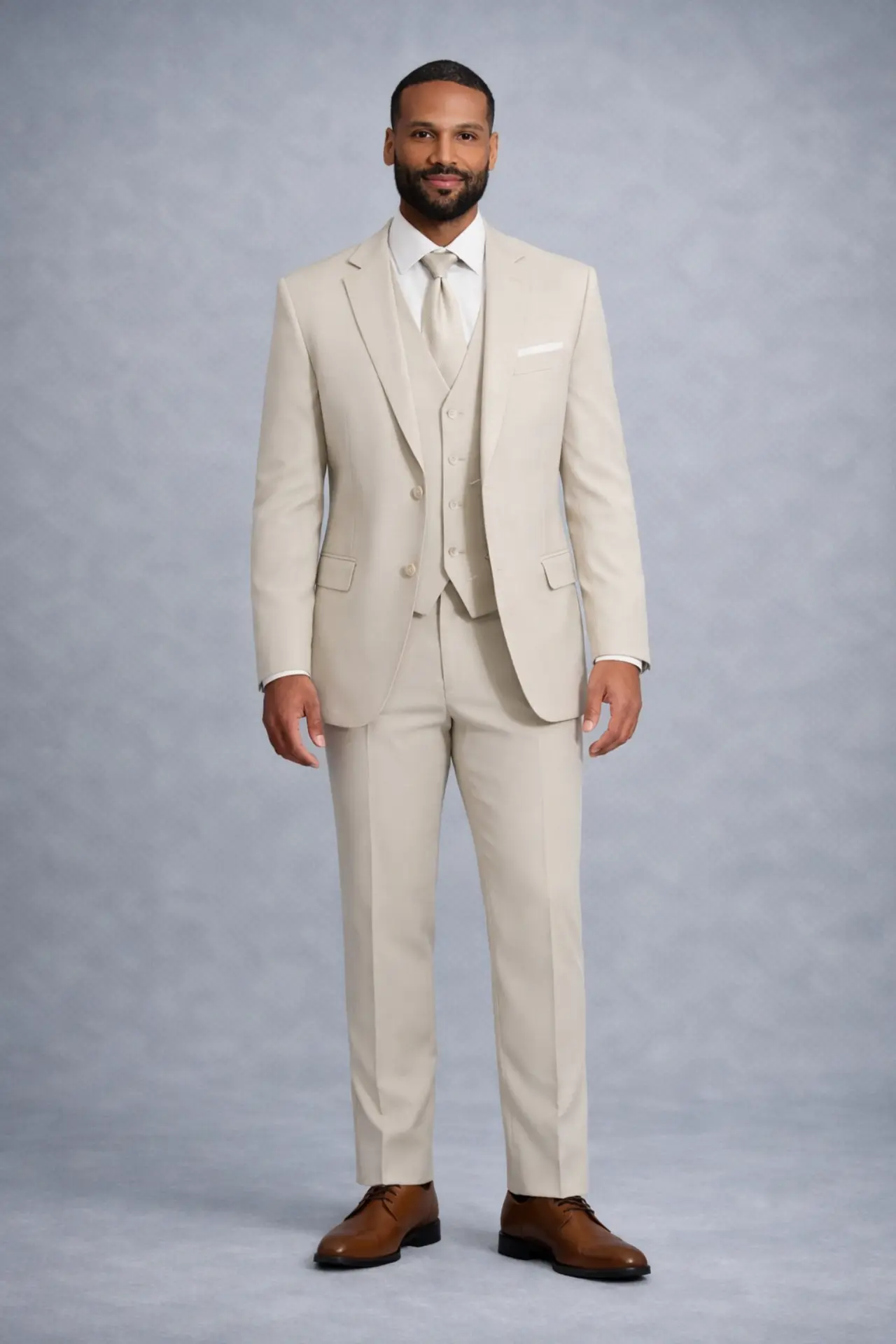 Traje crema (tan) de tres piezas con chaleco, corbata tono sobre tono, pañuelo de bolsillo y zapatos café, cuerpo completo fondo blanco — renta para novios y cortejos en Masculino.do