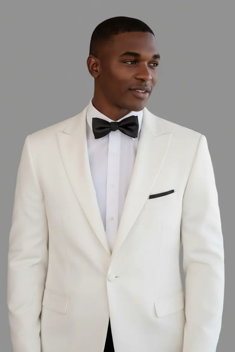 Detalle de esmoquin marfil con solapa peak ribeteada en negro y corbatín negro, primer plano — Masculino.do
