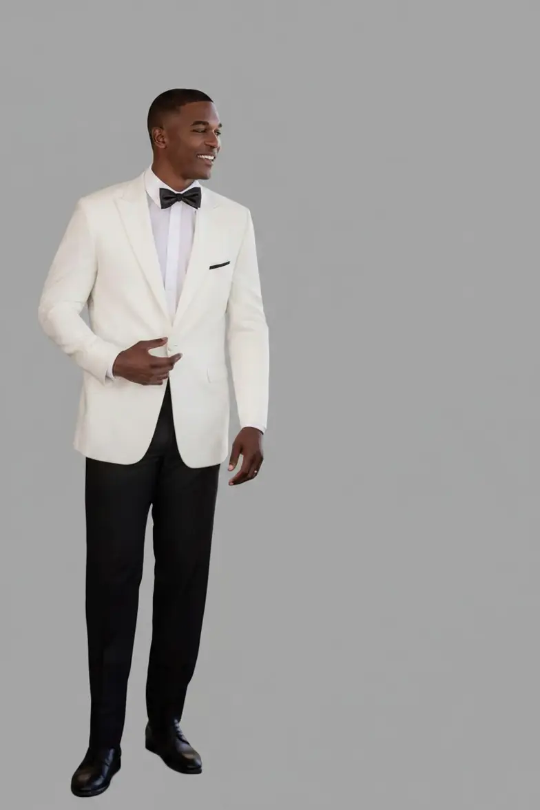 Esmoquin marfil solapa peak, pantalón negro, sonriendo de lado, cuerpo completo fondo gris — Masculino.do