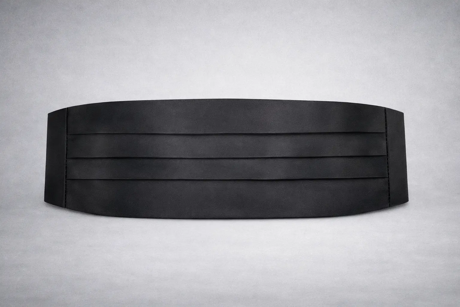 Fajín negro de raso con pliegues horizontales para tuxedo y esmoquin, vista frontal sobre fondo gris — Masculino.do