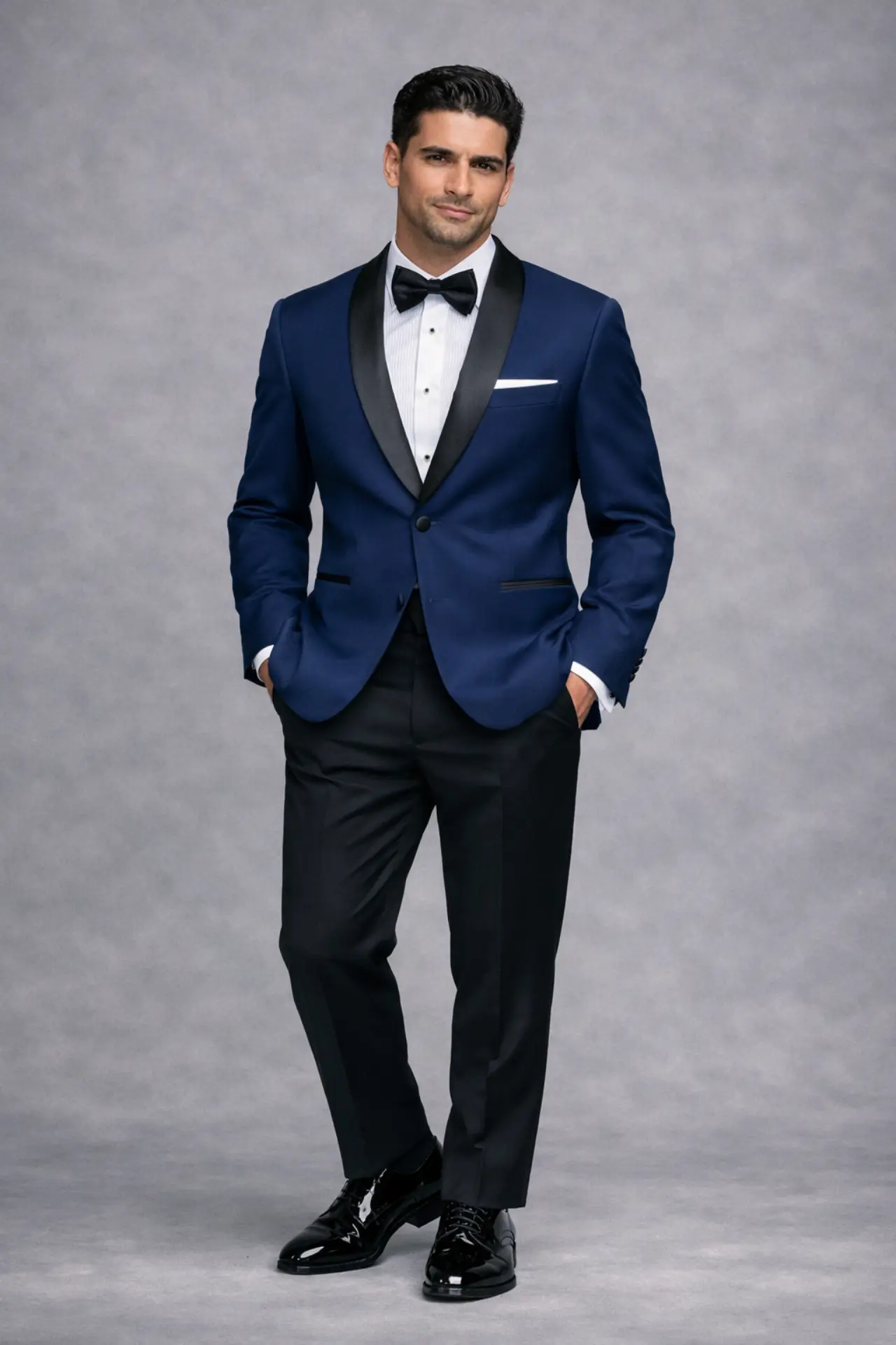 Tuxedo navy con solapa shawl en satín negro, corbatín negro, pañuelo blanco y pantalón negro, cuerpo completo fondo gris — Masculino.do