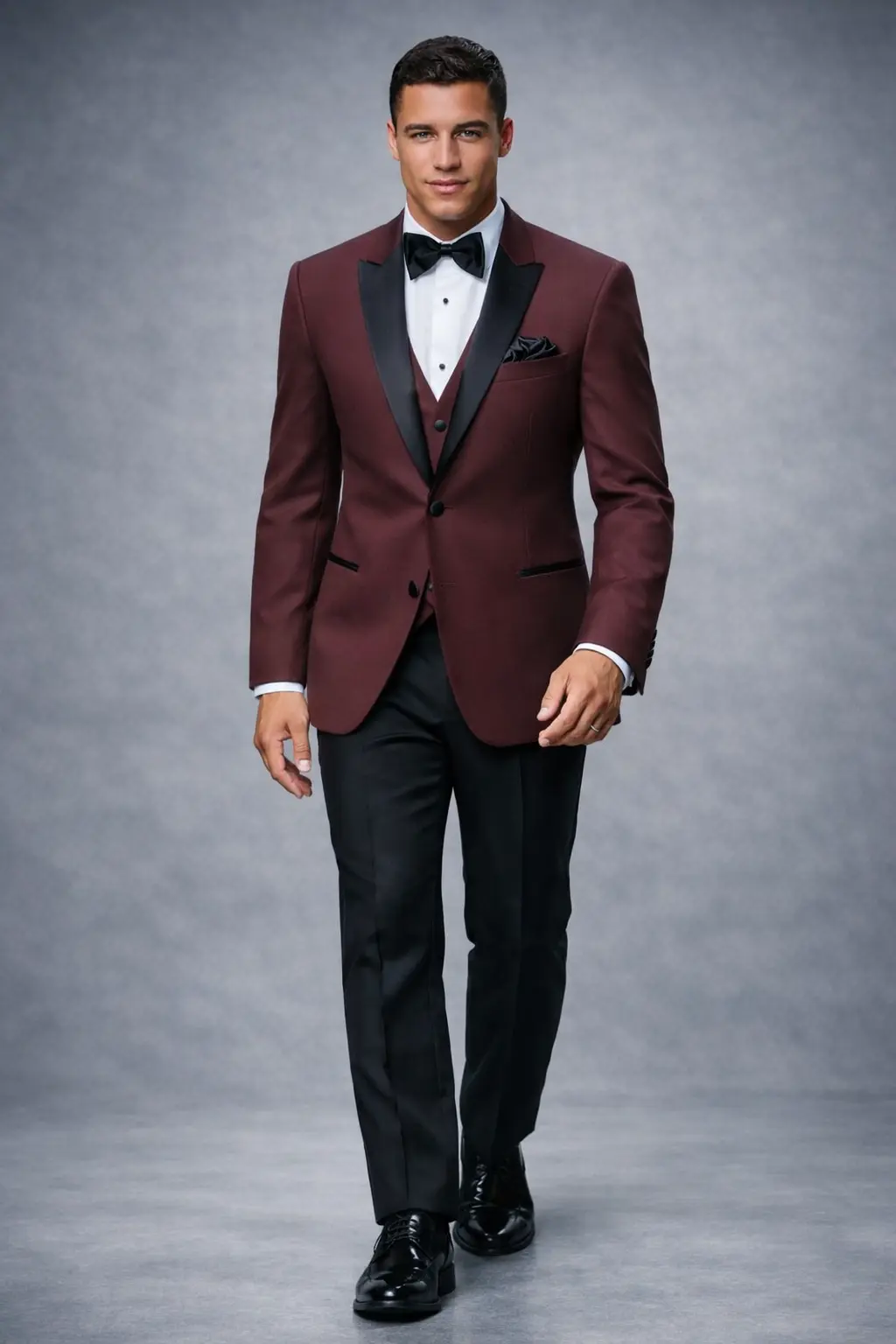 Tuxedo Marbella Burgundy con chaleco, solapa peak en satín negro, corbatín negro y pantalón negro, cuerpo completo fondo gris — Masculino.do
