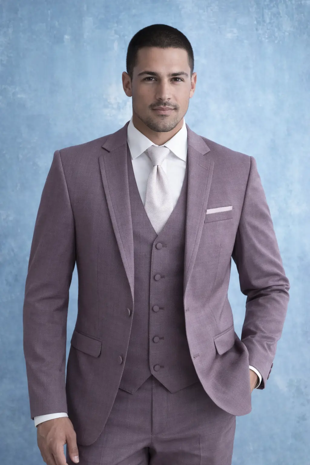 Suit Mulberry tres piezas con chaleco tono sobre tono, corbata blanca satinada y pañuelo rosa — primer plano look de novio fondo azul — Masculino.do