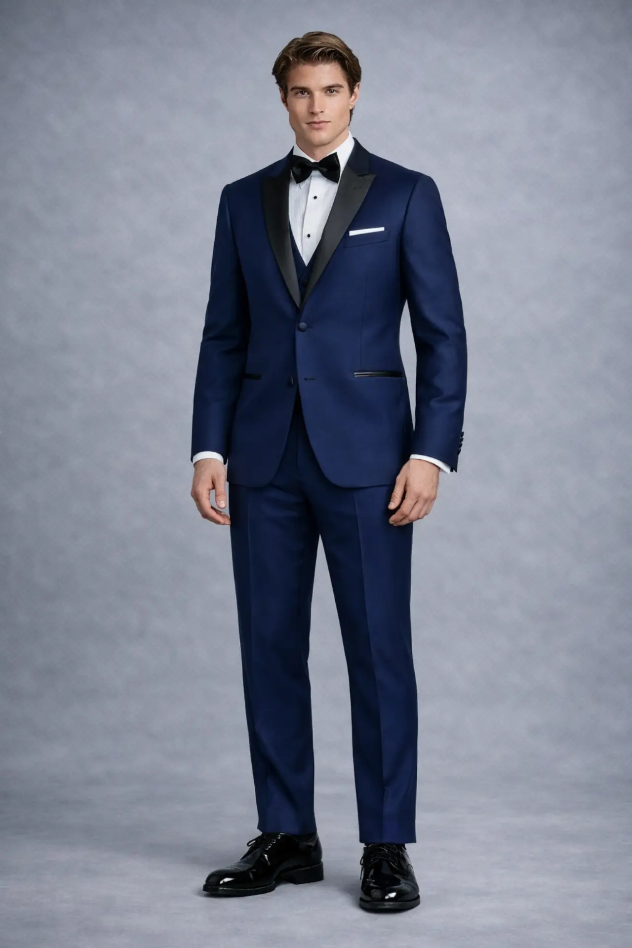 Tuxedo navy completo con solapa peak en satín negro, corbatín negro, pañuelo blanco y pantalón navy, cuerpo completo fondo gris — Masculino.do