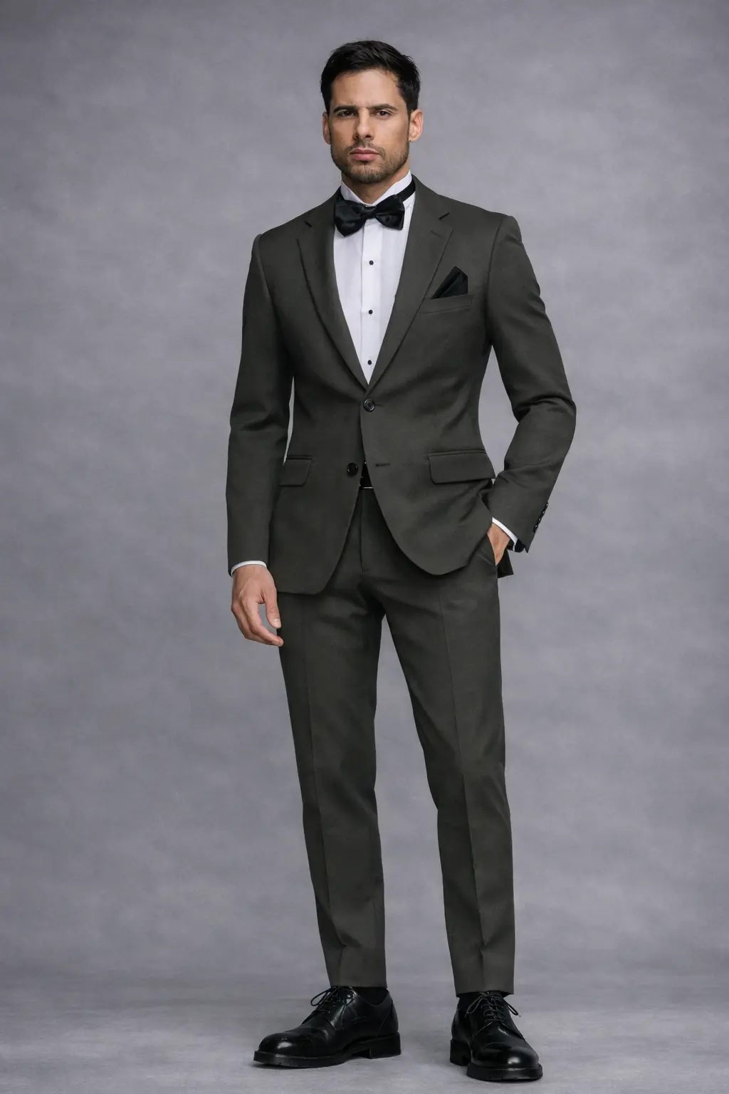 Tuxedo verde oliva con solapa Peak en satín, corbatín negro satinado, pañuelo negro y zapatos oxford negros — cuerpo completo fondo gris — Masculino.do