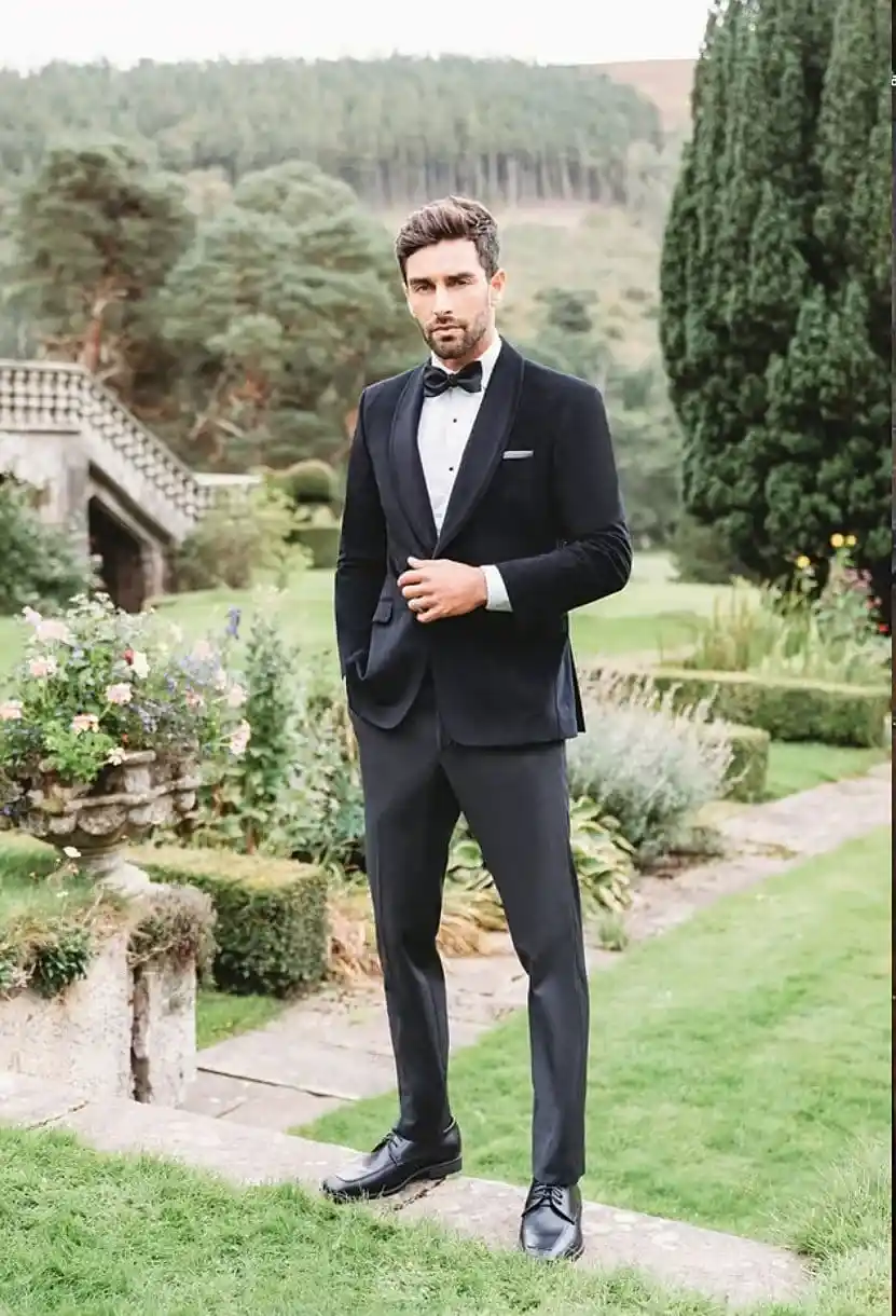 Caballero con esmoquin negro de solapa shawl, corbatín negro y pañuelo blanco, posando en jardín elegante — Masculino.do