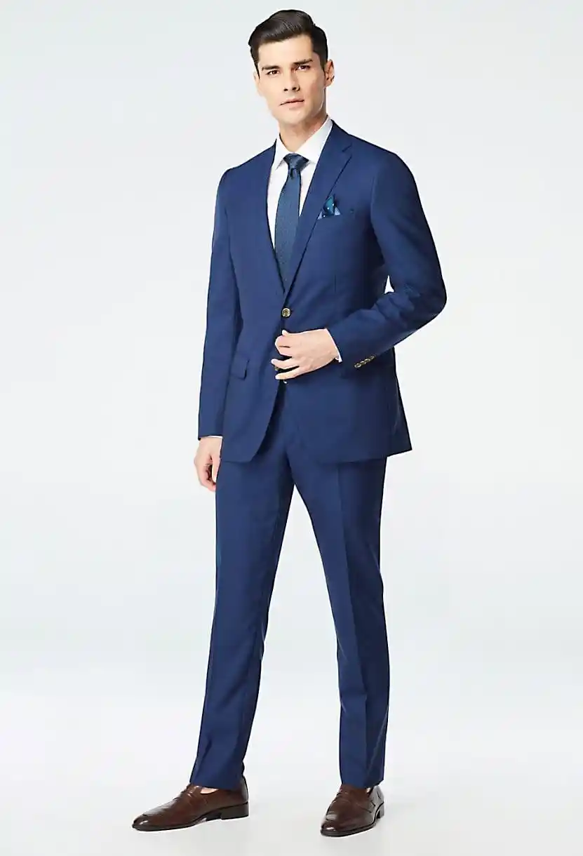 Traje azul zafiro slim fit de cuerpo completo con corbata azul, pañuelo de bolsillo y mocasines café, fondo neutro — confección a medida en Masculino.do