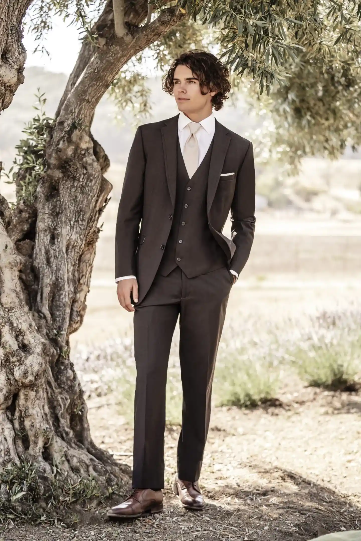 Primer plano de traje marrón de tres piezas con chaleco, solapa peak, corbata beige y pañuelo de bolsillo al aire libre — Masculino.do